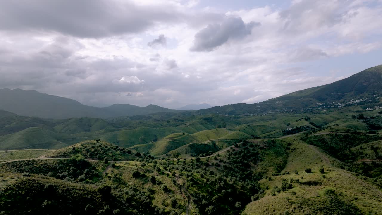 Ripresa con drone ad alta risoluzione che mostra dolci colline e catene montuose nella regione di Marbella, Andalusia, sotto un cielo sereno