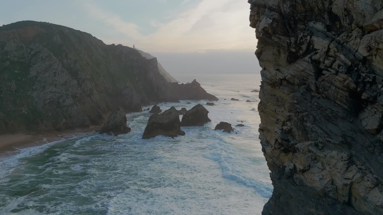 fotografía aérea de la playa de ursa con olas espumosas y rocas durante la puesta de sol dorada en portugal