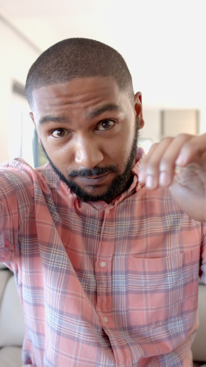 Vertical video: Smiling man in plaid shirt taking selfie during friends hangout at home