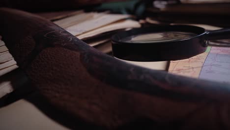 antique manuscripts and artefacts clutter explorers desk in moody room
