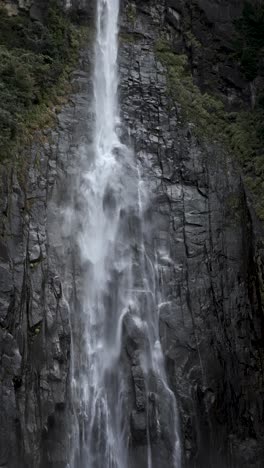 majestic nachi falls flowing down a towering rock face in a serene environment. vertical video, slow motion
