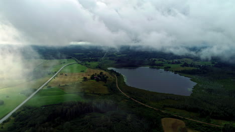 Toma-Aérea-Hacia-Atrás-Del-Hermoso-Paisaje-Rural-Con-Praderas-Verdes-Y-Pequeños-Lagos-Visibles-Durante-El-Día-En-Un-Día-Nublado