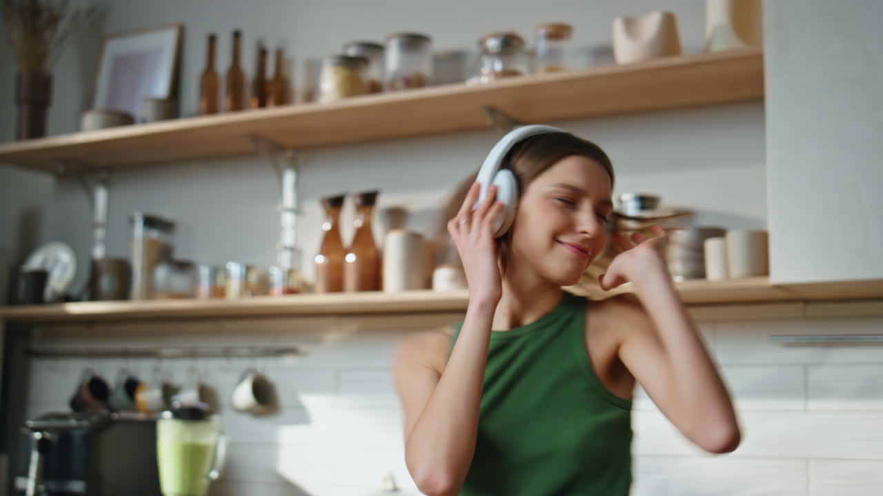 Woman dancing in the kitchen with milk and headphones