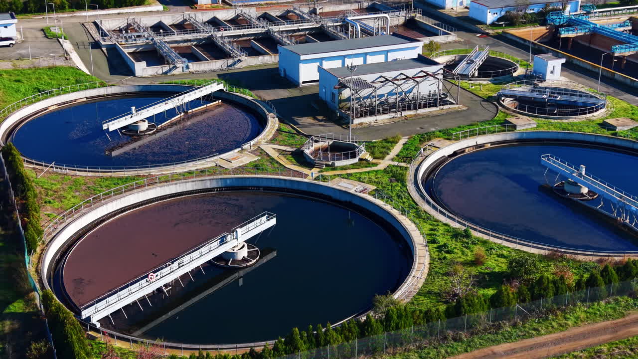 Detailed high angle shot of large circular sedimentation tanks and rectangular filtration basins at a modern water treatment facility
