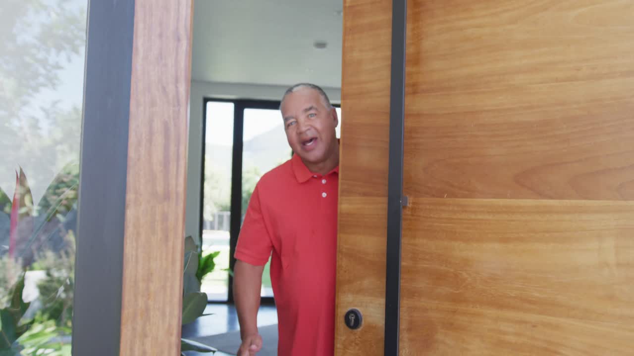 Portrait of happy senior biracial man opening door at retirement home