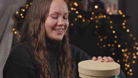 young girl's december surprise: radiant smiling brunette opens christmas present but is disappointed