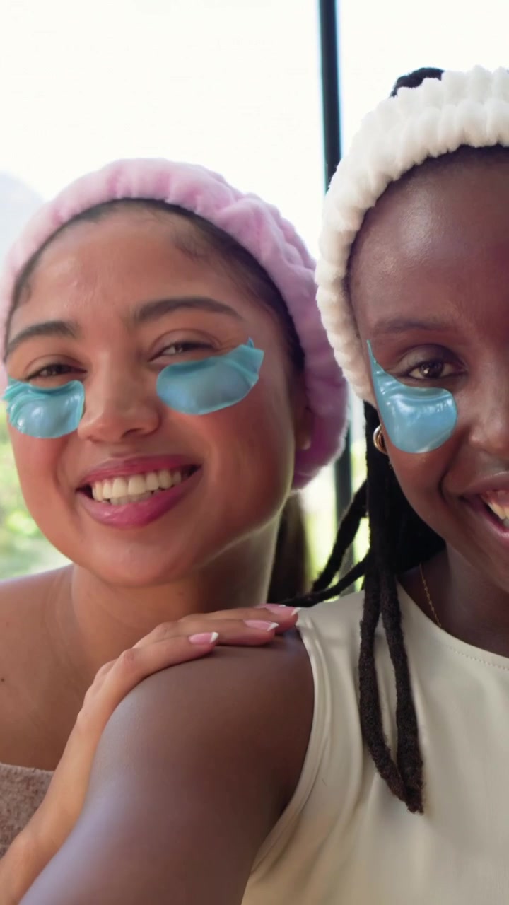 Vertical video: Smiling women leaning in and laughing as camera starting by window, wearing patches