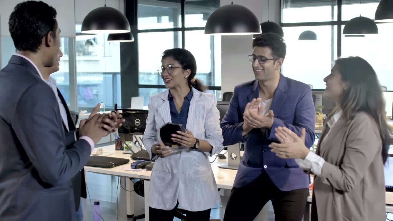 여성 동료의 성공을 축하하는 웃는 혼합 성 사무실 직원