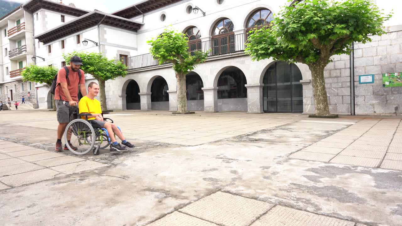 Uomo che spinge un bambino in sedia a rotelle nella piazza della città