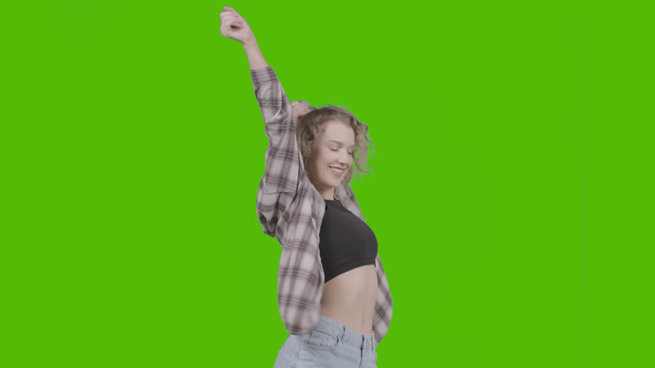 foto de estudio de una joven que se divierte bailando contra una pantalla verde