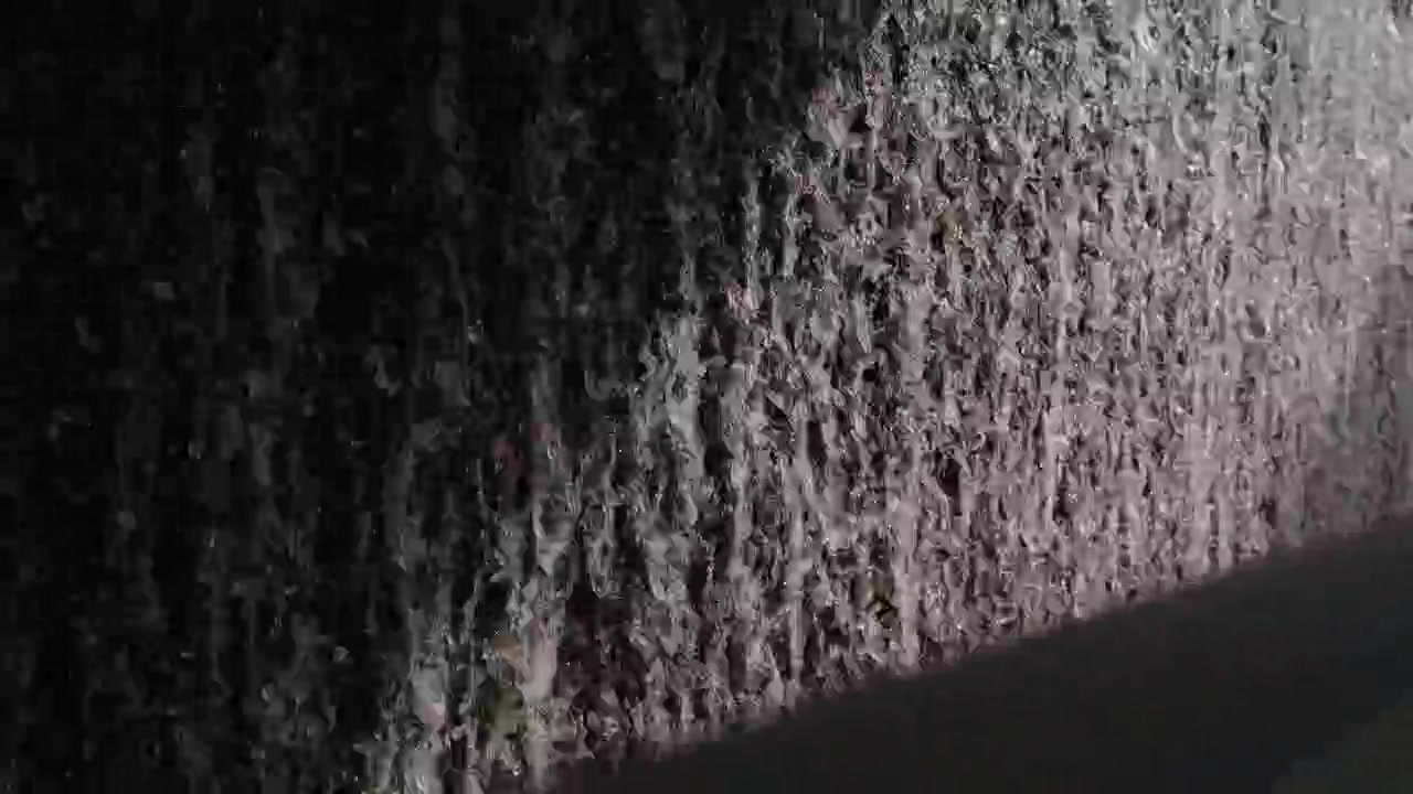 Water cascading down dam wall closeup with foaming white texture dramatic light and shadow