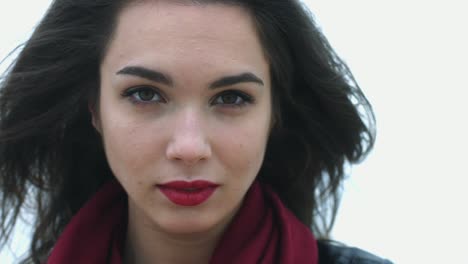 portrait brunette woman touching hair moving on wind and looking in camera