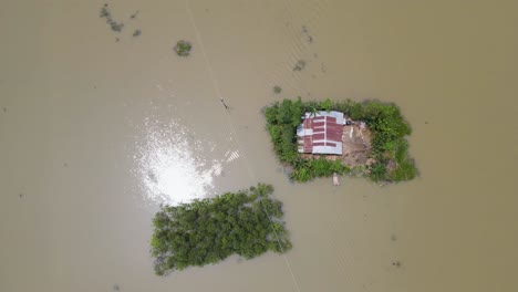aerial: isolated house surrounded by flood water in rural countryside of bangladesh, south asia