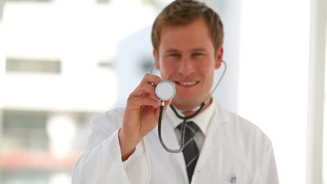 médico sosteniendo su estetoscopio mientras sonríe