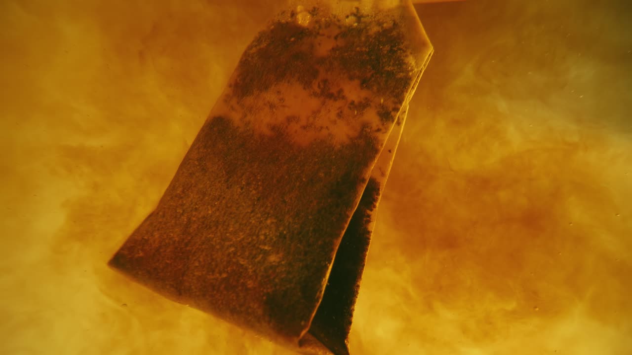 primer plano de la bolsa de té difundida en un vaso transparente. macro cámara lenta del proceso de elaboración de hierbas.