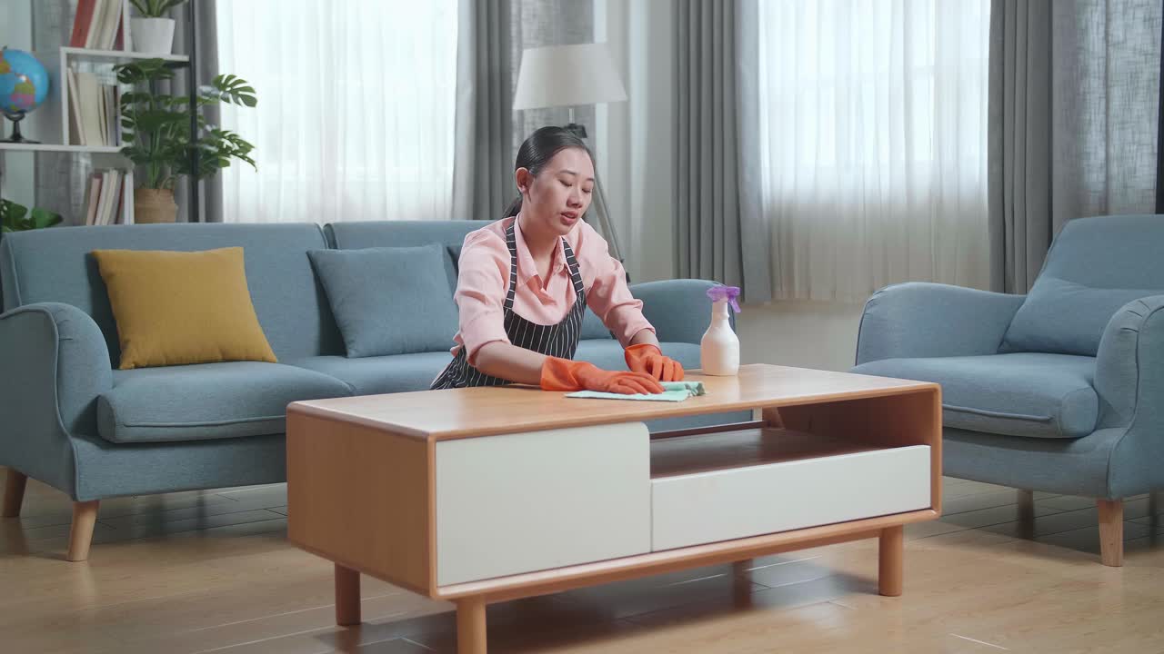 거실 에서 커피 테이블 을 청소 하는 여자