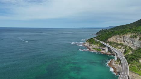 aerial near cliffs to reveal traffic on the sea cliff bridge in nsw with pacific ocean beyond