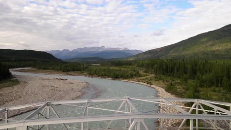 drone volando sobre un puente sobre las aguas turquesas del río toad en el paisaje natural del norte de columbia británica, canadá