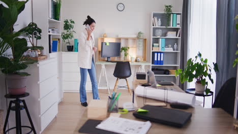 businesswoman walks around office talking on mobile phone