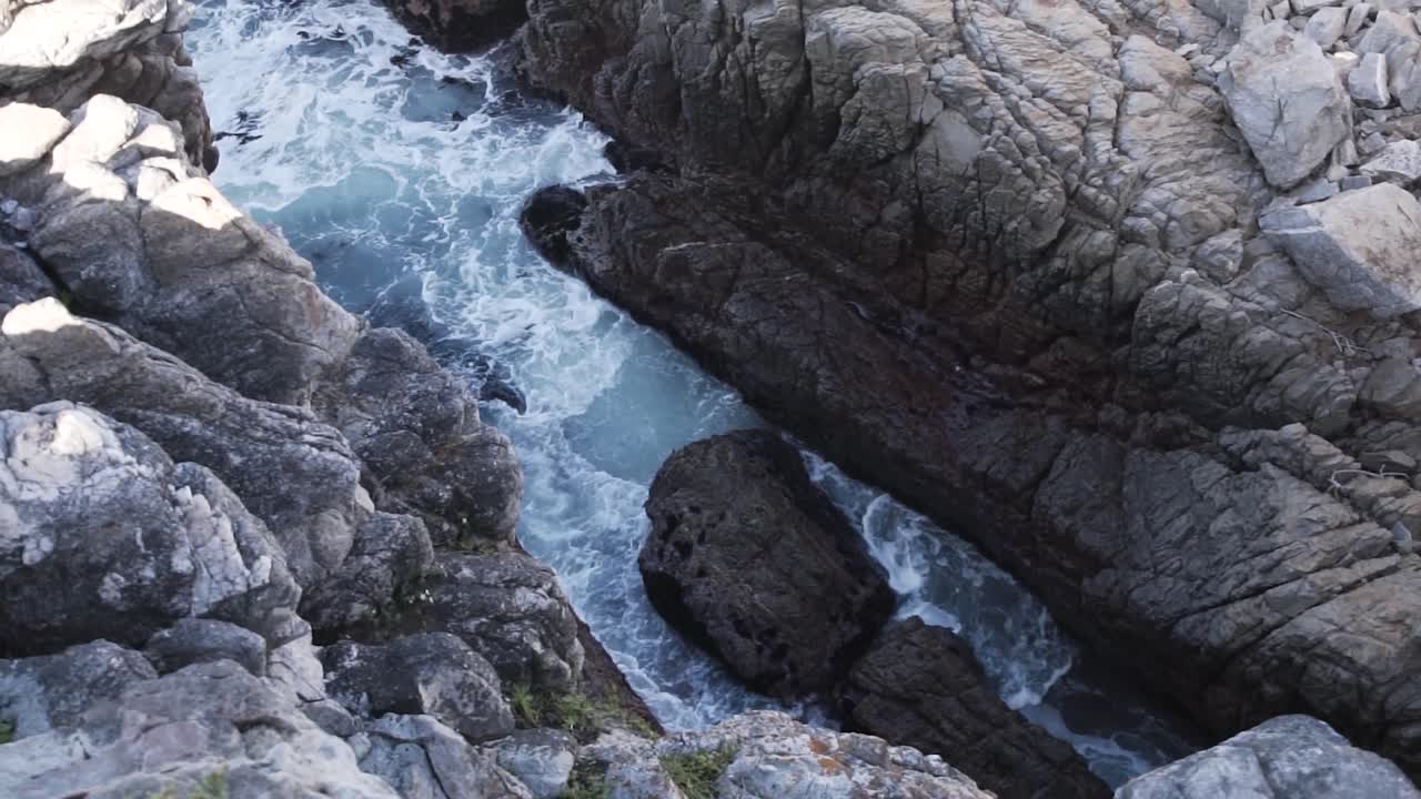 Onde spumeggianti si infrangono contro le scogliere rocciose in estate in Sudafrica
