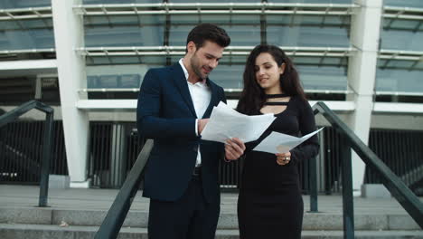Young-business-couple-analyzing-documents-outside