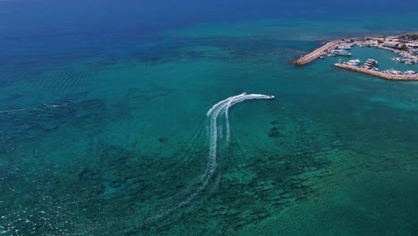 Areal-shot-of-speed-boat-and-towable-water-tube-ring-tourist-action-sport-in-Ayia-Napa-harbor-marina