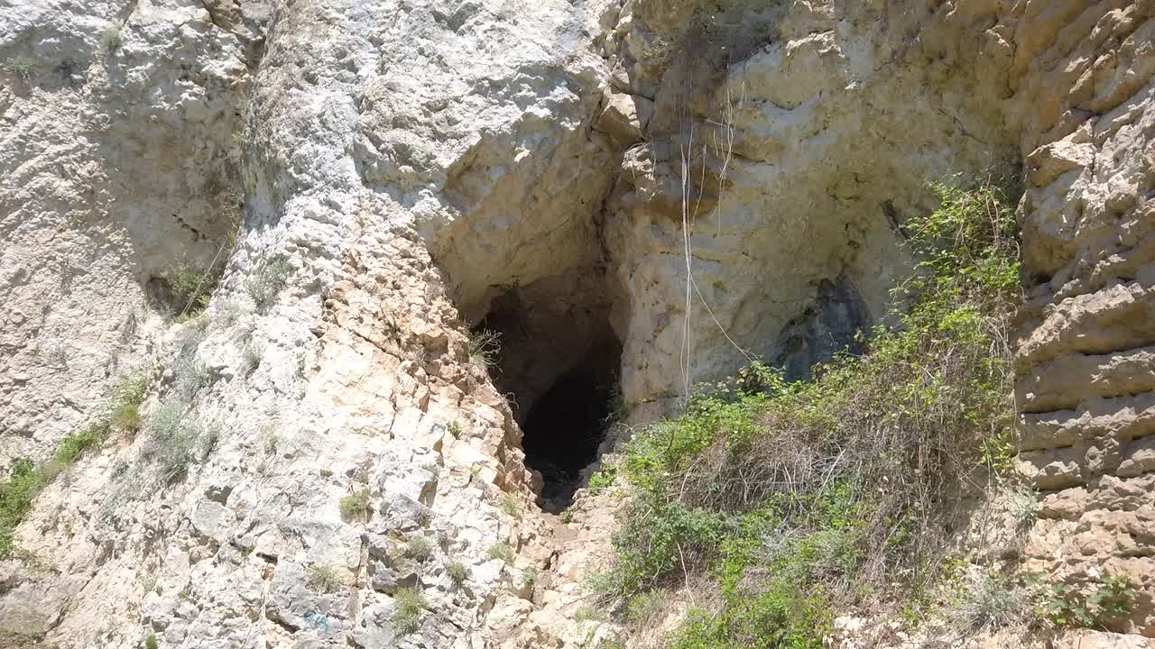 Limestone rock composed of slabs, cracks, overhangs and caves. Diverse, rocky terrain suitable for sport climbing. Green vegetation. Sunny day in the nature of Bulgaria. Pan left
