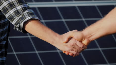 Handshake-Of-Two-Businessmen-On-A-Background-Surface-Of-Solar-Panels