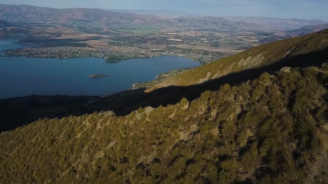 산 가장자리를 따라 내려가는 드론 샷은 광활한 계곡과 호수를 배경으로 드러납니다.