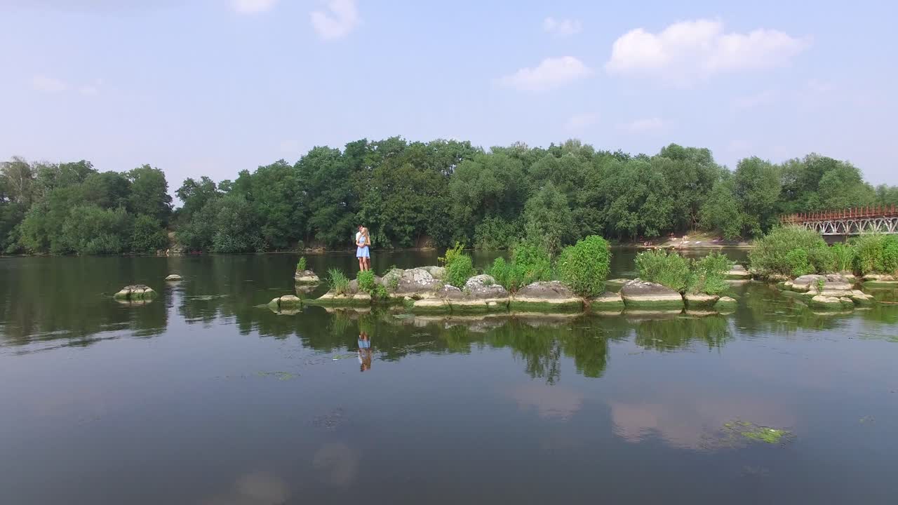 Young Couple Resting On The River. Aerial shot of a guy and girl in the relationship enjoying near water