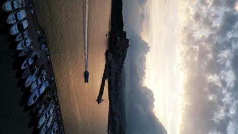 the drone is flying forward over a harbour in a timelapse where you see the boats sail and the clouds coming in ibiza spain aerial footage 4k