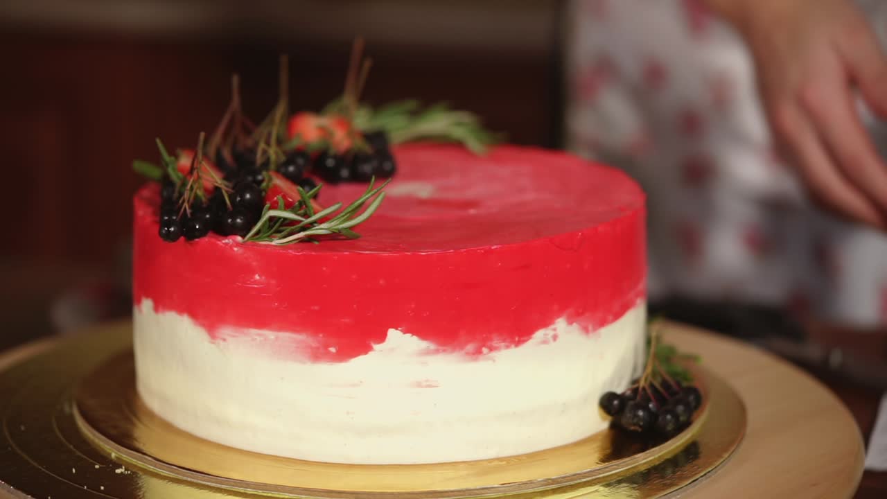 mujer decorando un pastel de terciopelo rojo con bayas