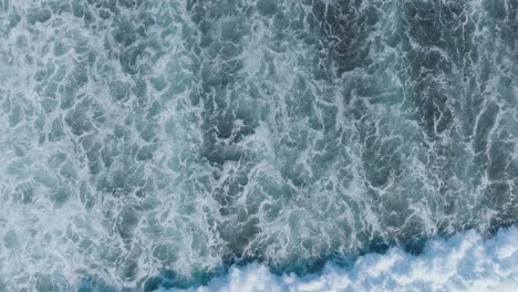 Top-Down-Slow-Motion-Drone-shot-of-abstract-wave-motion-and-patterns-in-Uluwatu-Bali-Indonesia