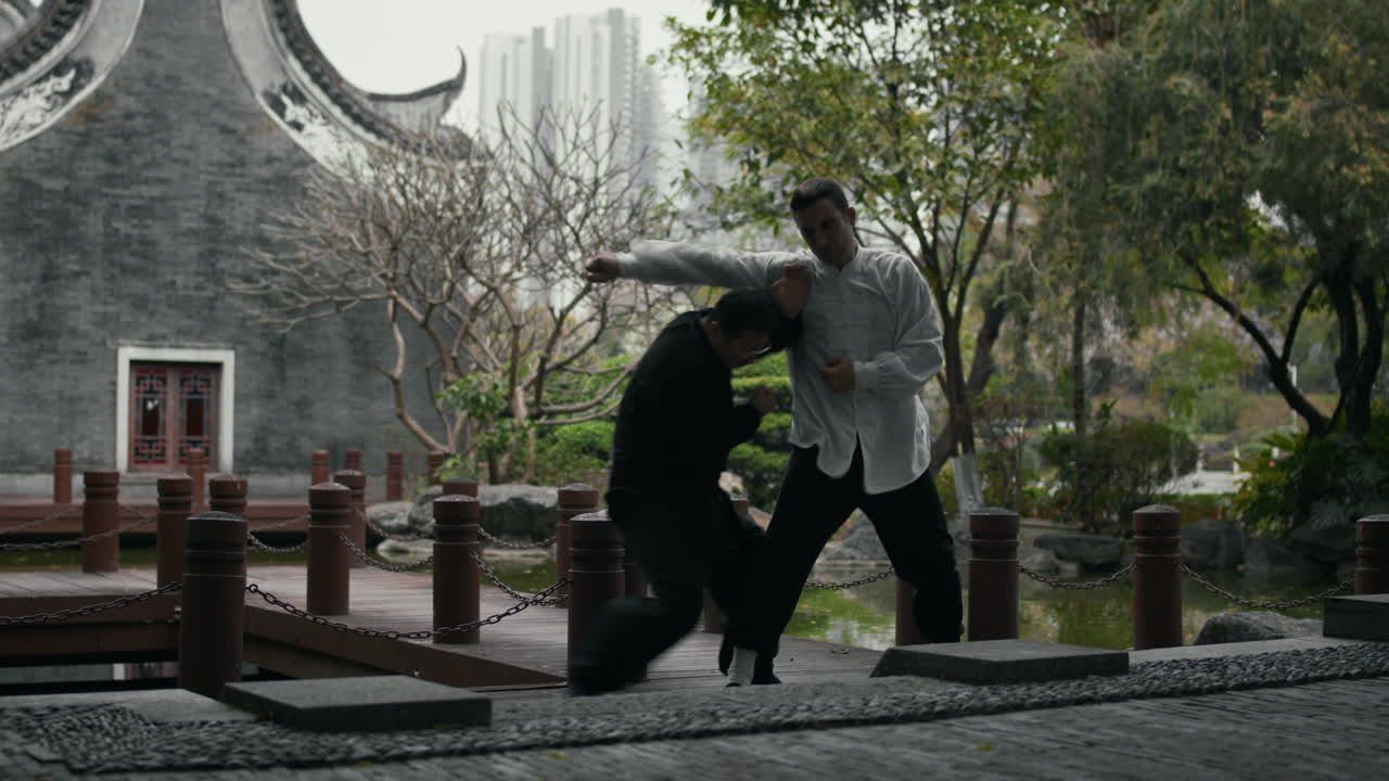 Two men practicing martial arts in a traditional Asian garden