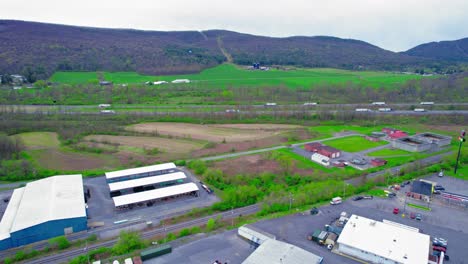 elevated view of semi trucks transporting goods on a highway through green rural areas in pa