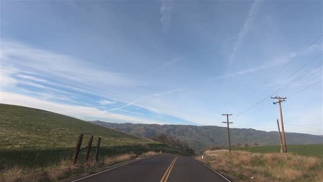 driving through california countryside with green fields and foothill mountains