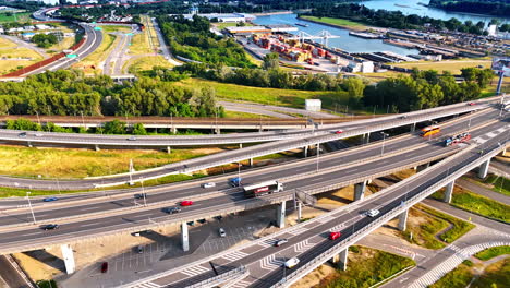 european truck-filled junction. trucks navigate a complex highway junction near a river and industrial area during daylight, showing urban activity