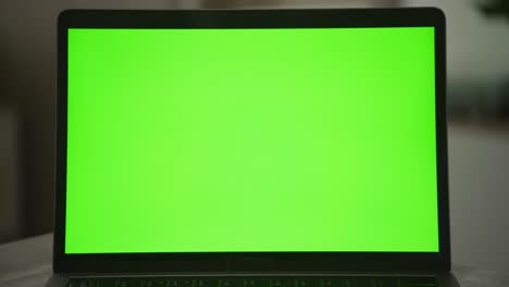 slow optical zoom out from a laptop computer screen with a green screen on it