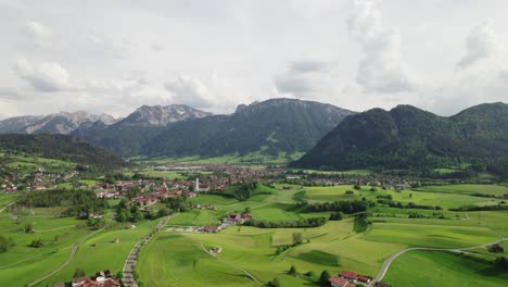 flying over a bavarian village in the alps with mountains in the background