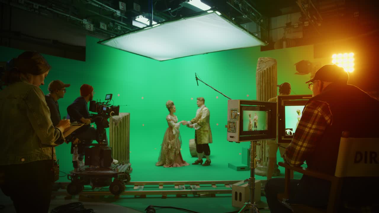en un gran estudio de cine, un equipo profesional filma una película de teatro de vestuario de historia. en el set: el director controla el camarógrafo grabando una escena en pantalla verde con dos actores talentosos con ropa renacentista hablando