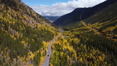 descending next to colorado highway surrounded by golden aspens in the fall, aerial