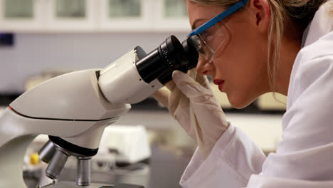 joven científico mirando a través del microscopio en el laboratorio