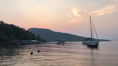 Boats-bobbing-on-waves-next-to-island-in-South-America-,-island-in-background-during-sunset