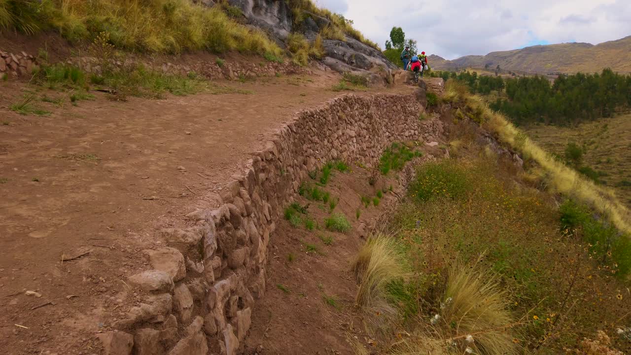 Close up view of Old Inca Trail, archaeological road leading to Huanacaure ruins near Cusco, Peru. Tilt up reveals tourists in the distance
