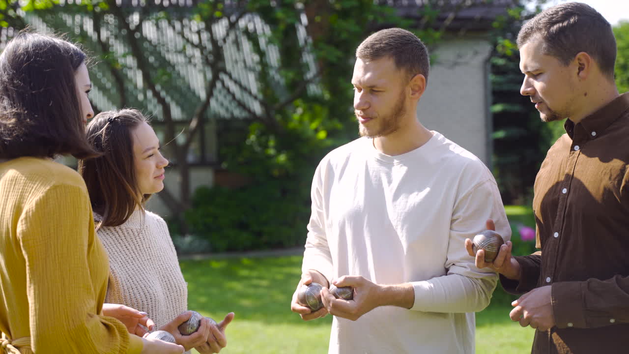 grupo de hombres y mujeres sosteniendo bolas de petanca en el parque y preparándose para protagonizar el juego