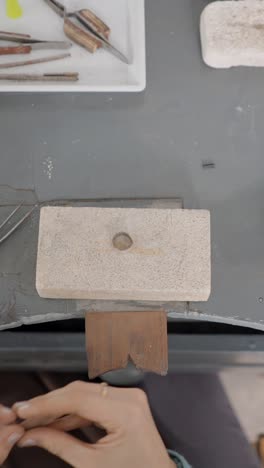 jewelry making workbench with tools and a hand
