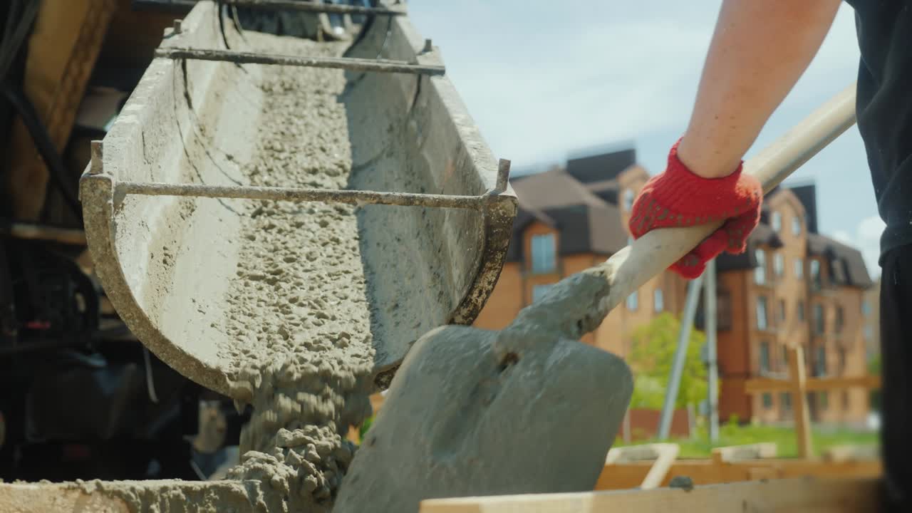 la construcción de una cabaña. los trabajadores toman el hormigón de una mezcladora en un encofrado de madera