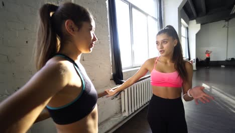 dos mujeres jóvenes teniendo una conversación en un estudio de baile