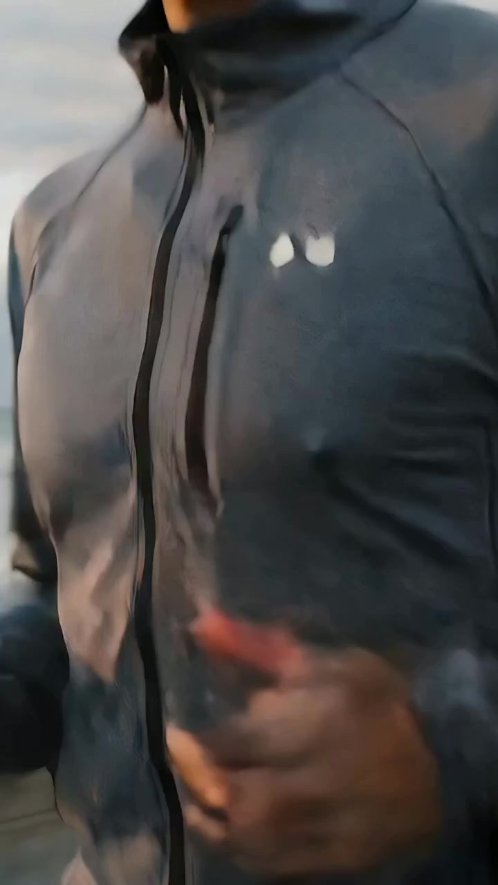 Vertical video: Jogging man responding to warm light swinging arms on pier, gray zip jacket pocket