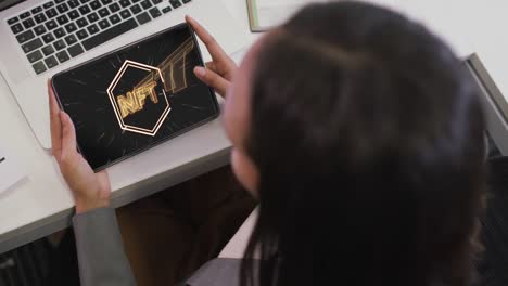 video de una mujer biracial trabajando en una tableta con nft en la pantalla